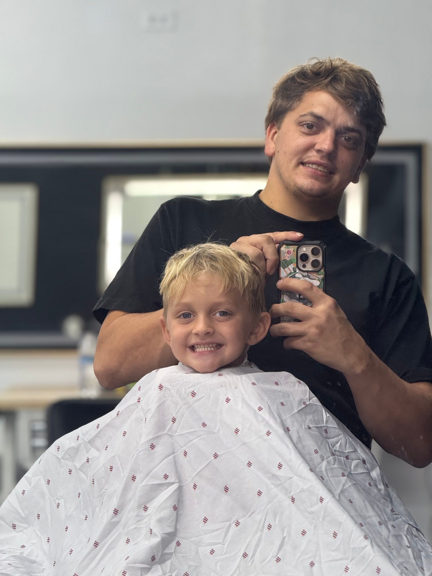 Sage The Barber smiling with a young client after a haircut at his shop in Stuart, FL